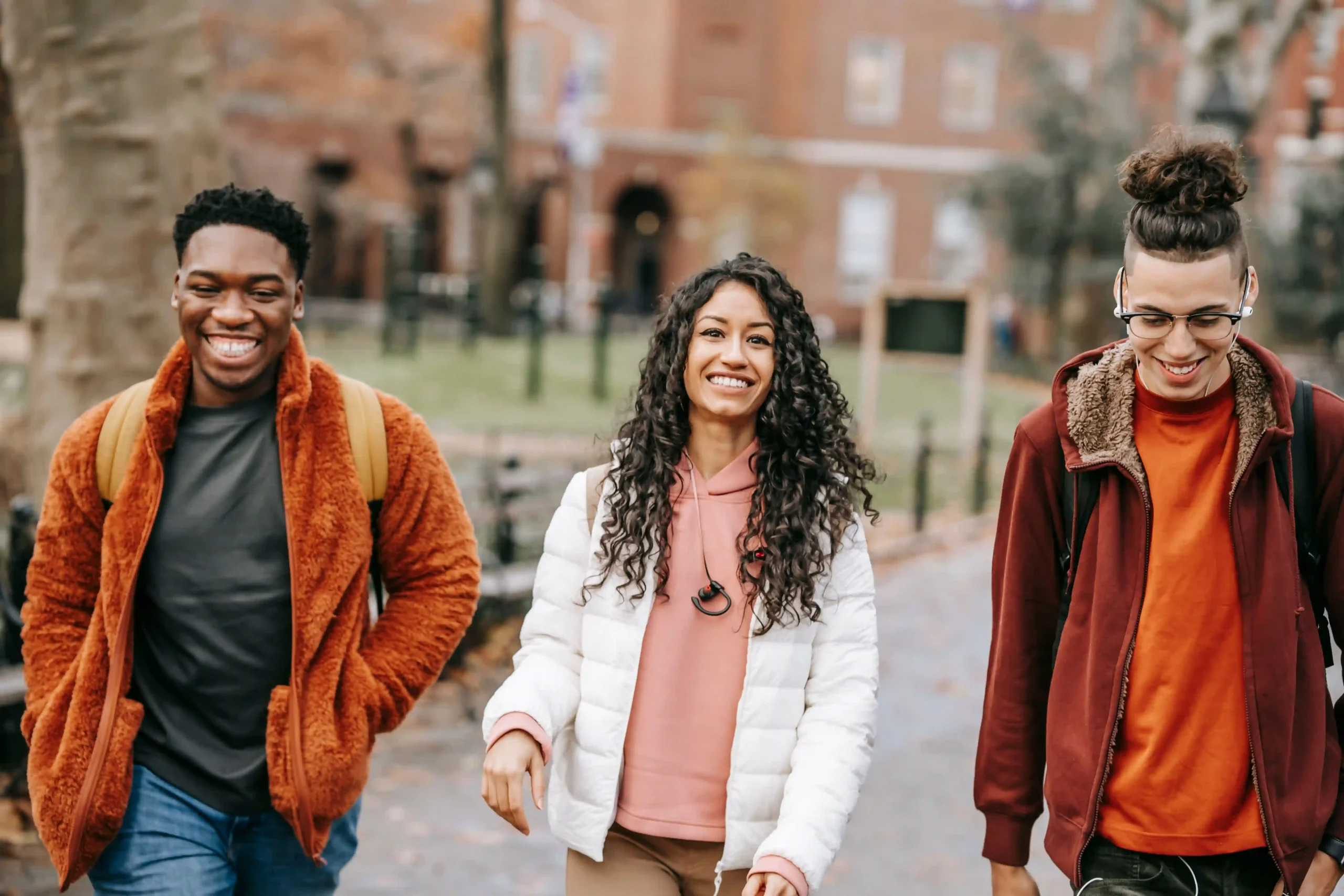 Three young individuals walking together on a sidewalk, engaged in conversation and enjoying their time outdoors.